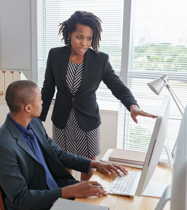 afro-american-woman-pointing-computer-screen-talking-junior-male-colleague-1